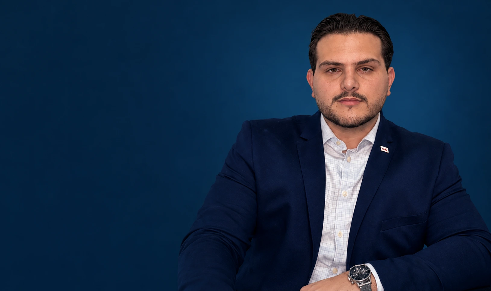Retrato de Anthony L. Brancher, sentado, usando blazer azul-marinho